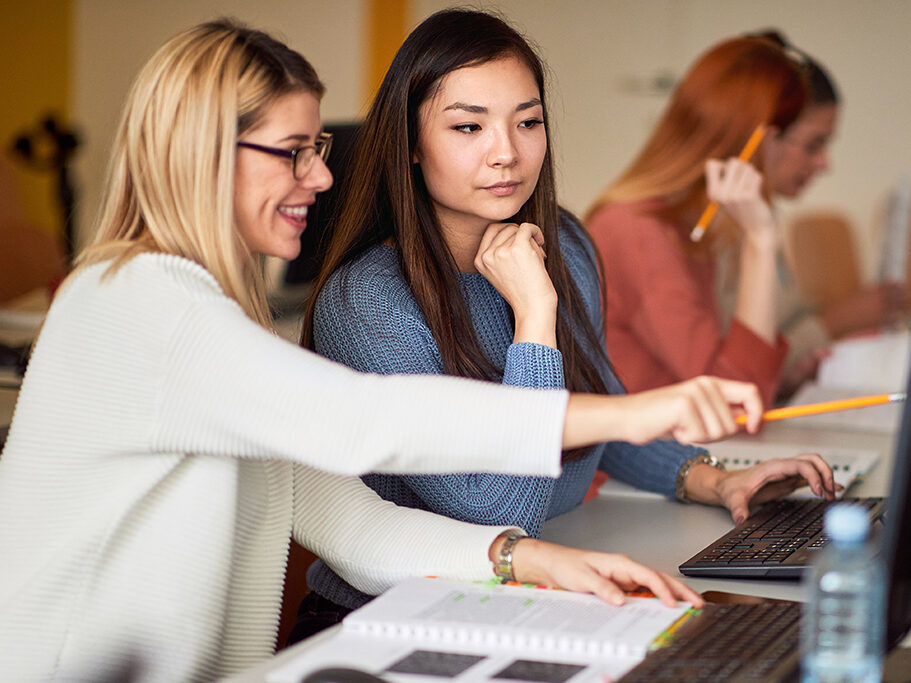 Two females learning from a laptop in class